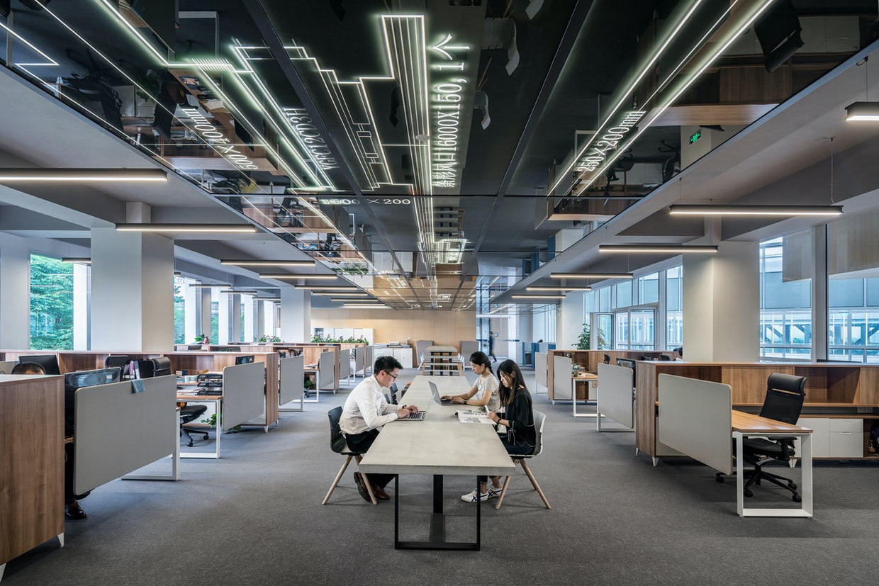 People working in a large open office with measurements and diagrams projected on the ceiling